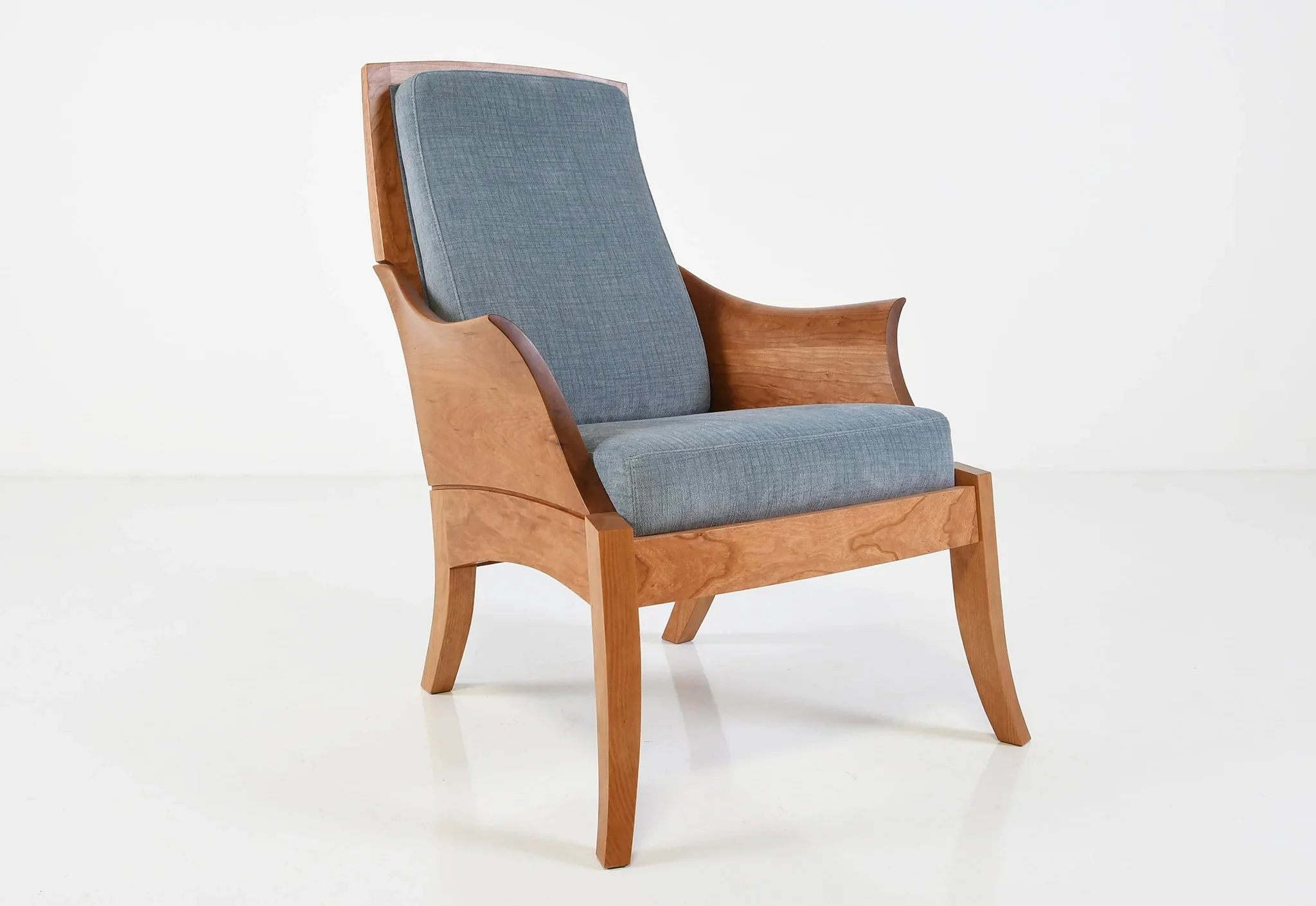 Chair - With curved arms sculpted from blocks of grain matched wood, the traces its lineage to an 18th-century chair