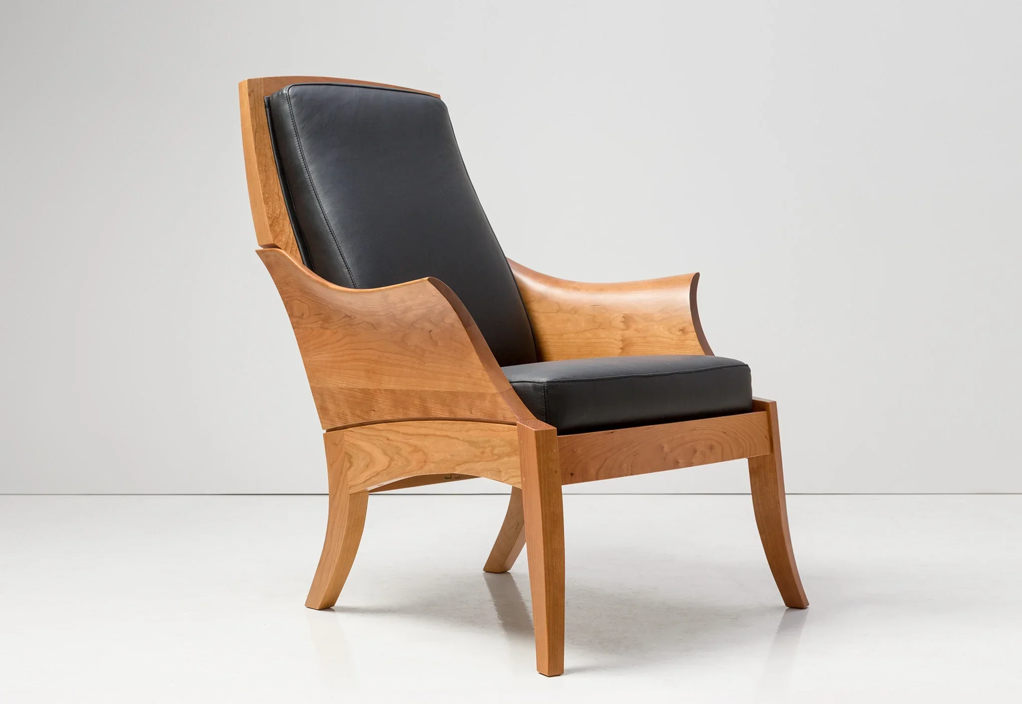 Chair - With curved arms sculpted from blocks of grain matched wood, the traces its lineage to an 18th-century chair